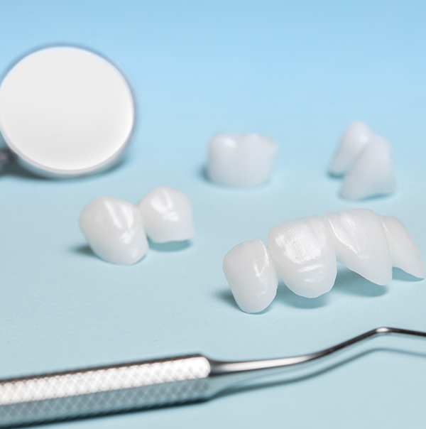 Several white dental crowns and veneers on a table