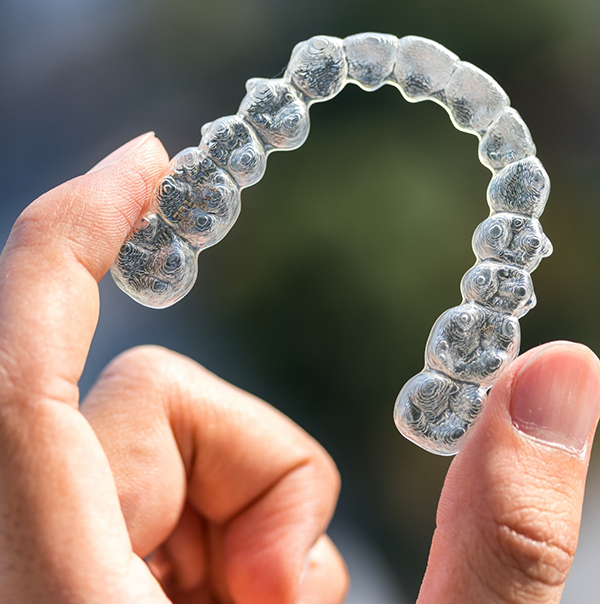 Hand holding an Invisalign clear aligner