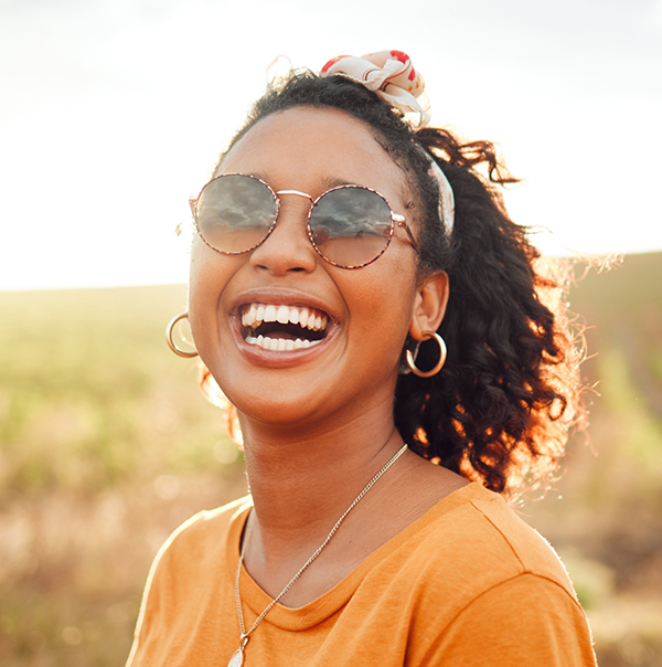 Woman laughing outdoors on a sunny day