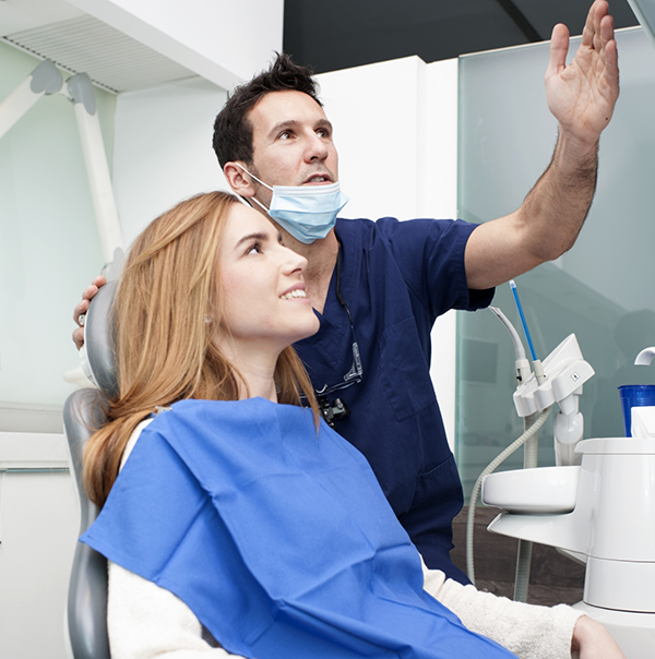 Dentist showing a patient something on a screen above the treatment chair