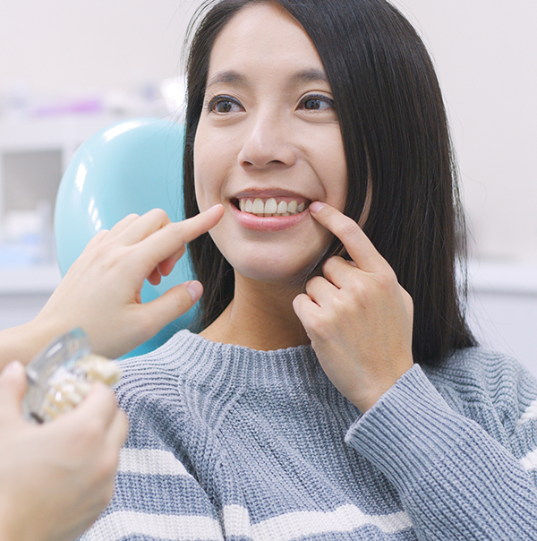 Woman pointing to her smile while looking at her dentist