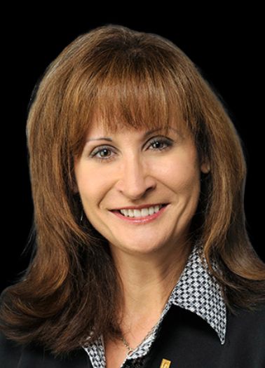 Woman with shoulder length brown hair smiling against black background