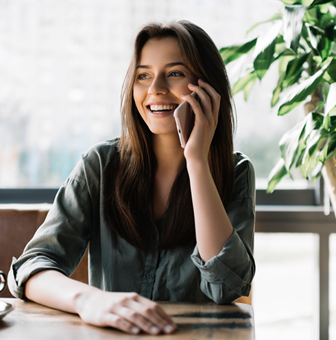 Woman sitting at desk and smiling while talking on phone