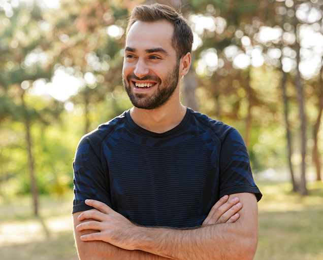 Smiling man standing in forest after replacing missing teeth in Virginia Beach