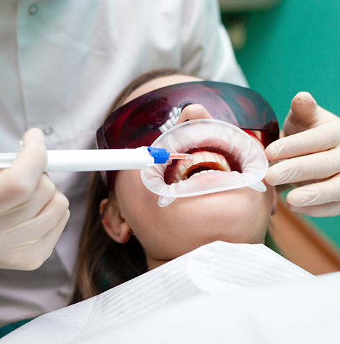 Woman receiving professional teeth whitening in dental chair