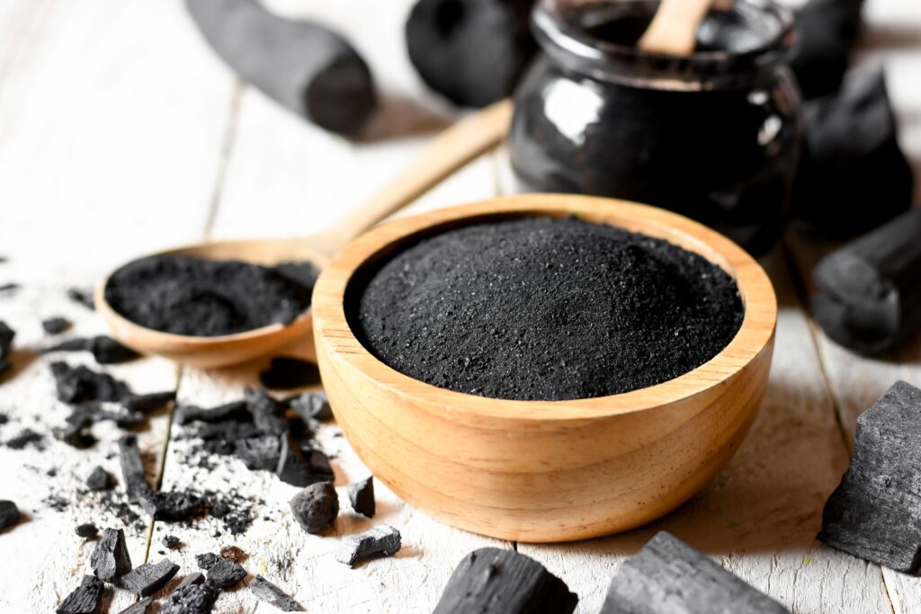 Pile of activated charcoal in an organic wooden bowl 